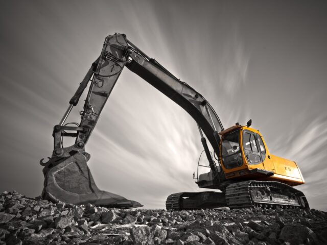 excavator-parked-on-stone-ground-against-dramatic-sky